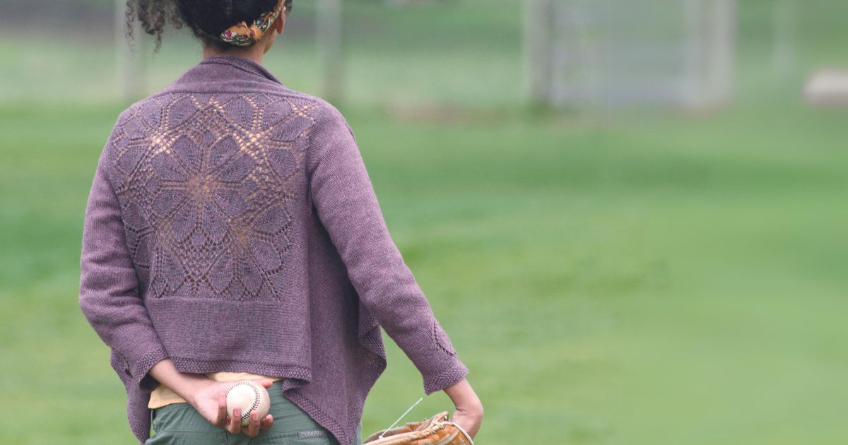 Dahlia Cardigan knitting pattern by Heather Zoppetti, a purple cardigan with a floral lace back