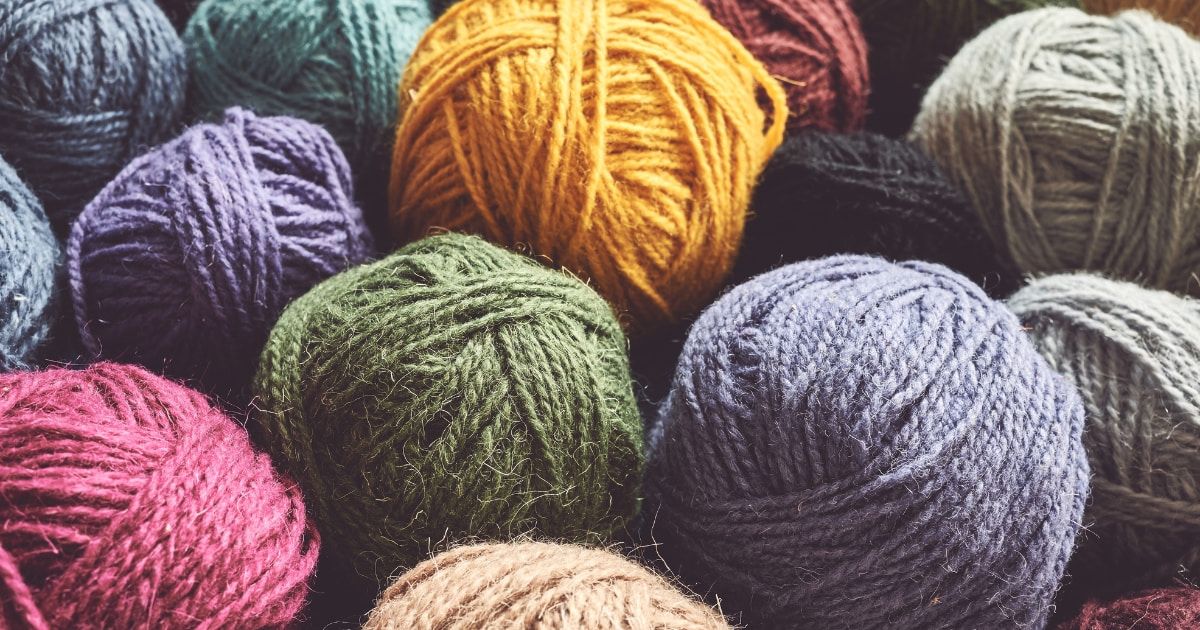 A variety of unlabeled yarn skeins and balls of yarn in muted colors