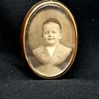 我发现一个美丽的胸针，里面装满了古老的黄金，里面有一个小男孩在一家古代店里的照片。