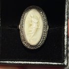 我为我女朋友买了这枚戒指作为圣诞节礼物。我对珠宝的历史了解不多。它是经过测试的纯银，但没有标记。浮雕由贝壳制成，周围环绕着白铁矿。你能告诉我什么吗？他几岁了？