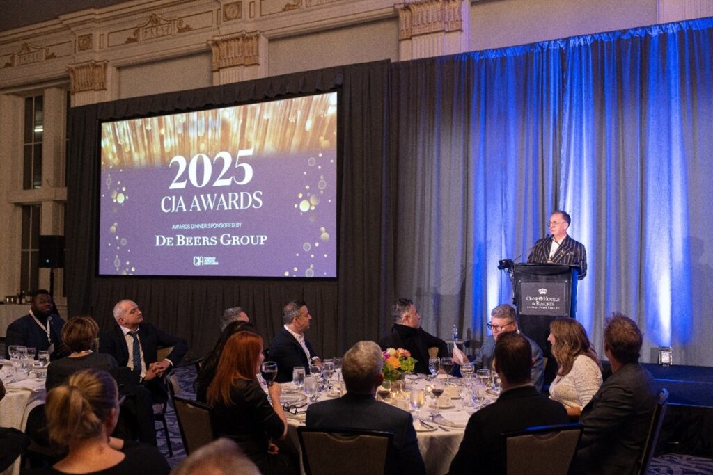 A group of business people seated at dinning tables, facing a speaker.