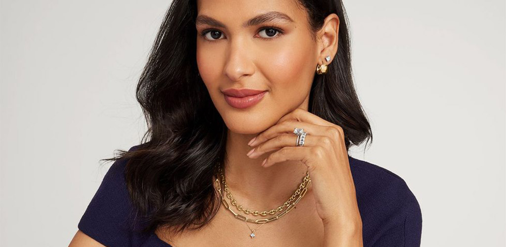 A close-up of layered necklaces and a diamond ring worn together, illustrating the importance of doing a gold or silver jewelry test.