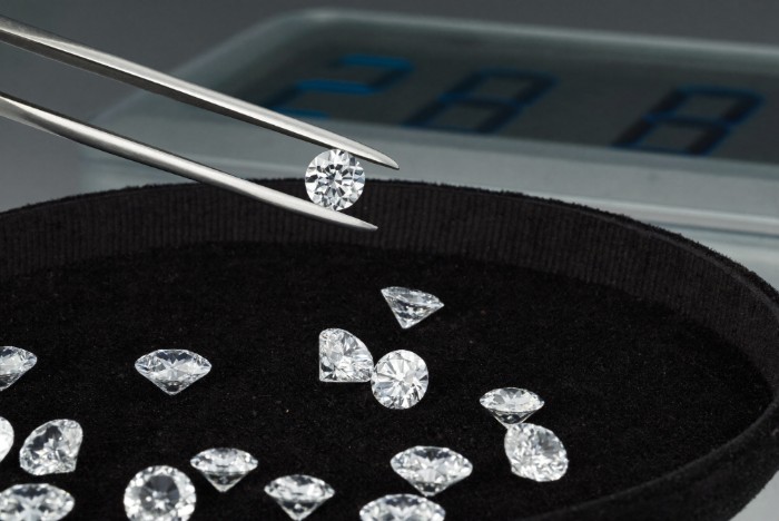 Lab-grown diamond prices Canada — loose lab-grown diamonds in tweezers over a suede gem tray