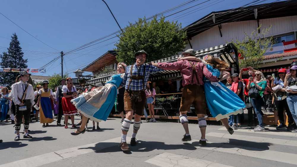 Men in lederhosen and women in dirndls dance during the parade at Oktoberfest.