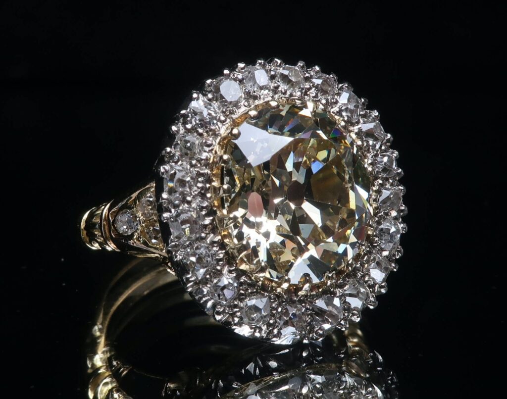 A large oval diamond ring surrounded with diamonds on a black baclkground.